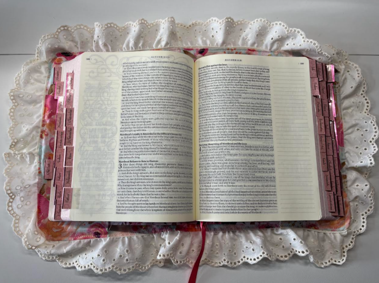 opened bible with lace trimmed bible sleeve on white background
